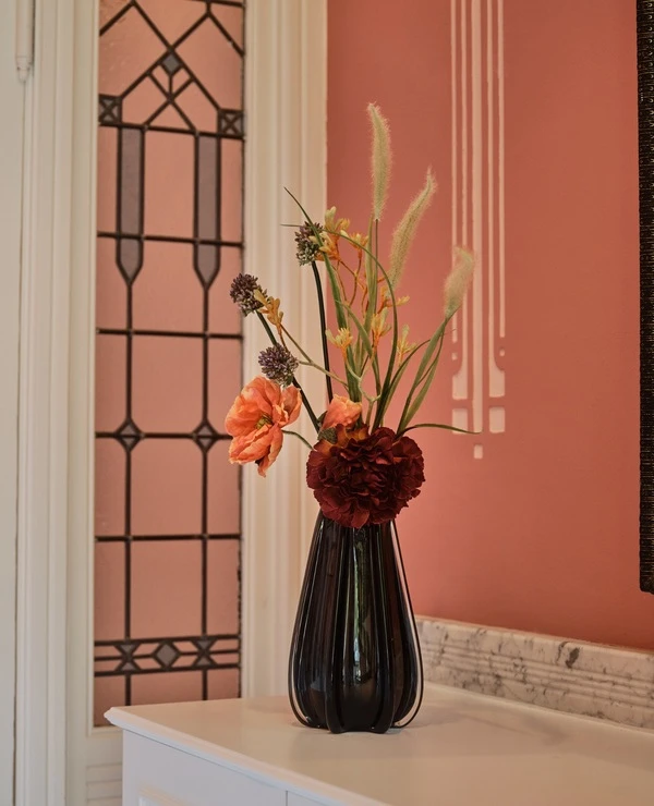 roze woonkamer met bruine vaas met rode en oranje bloemen van TICA